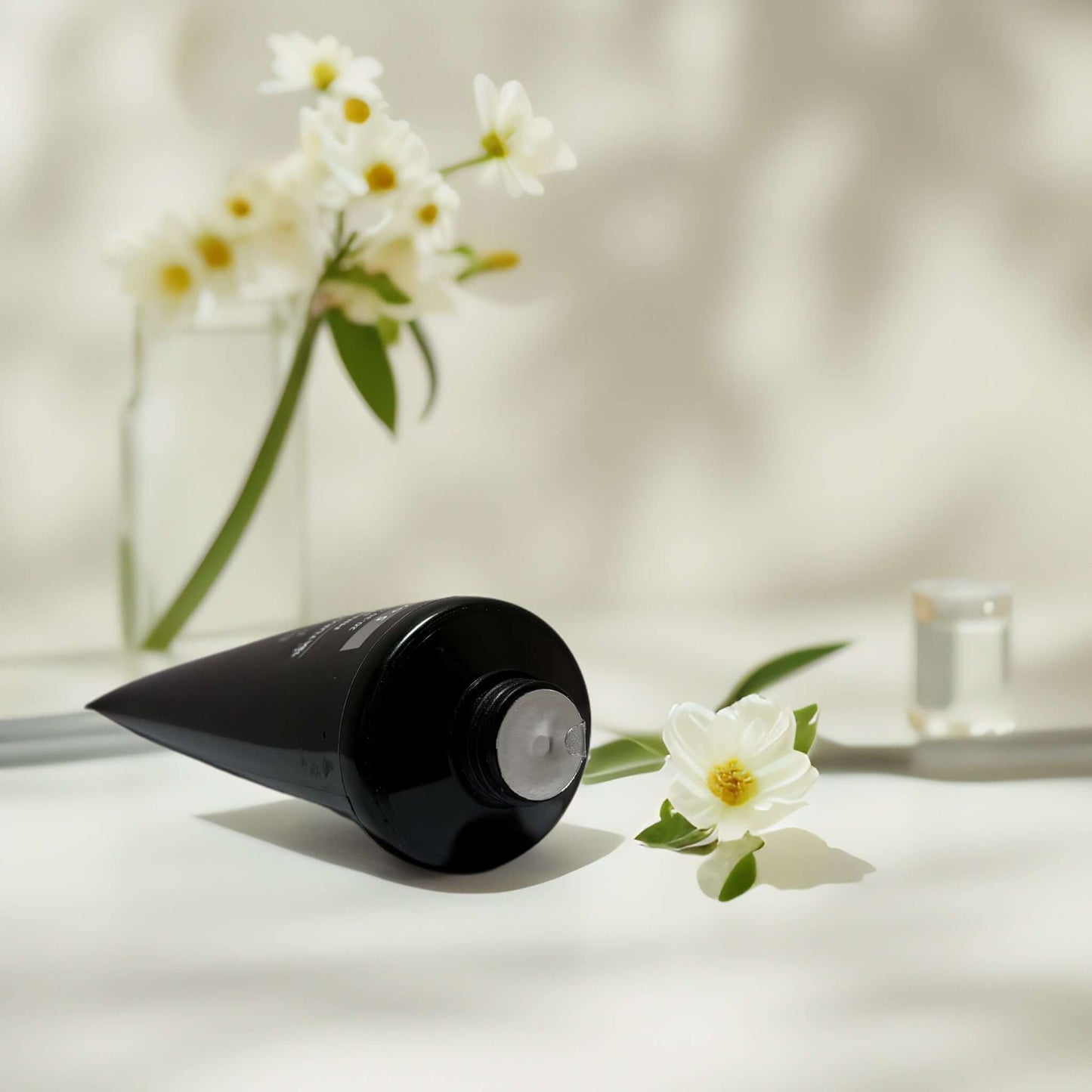 Deep Detox charcoal peel-off mask tube with flowers nearby.