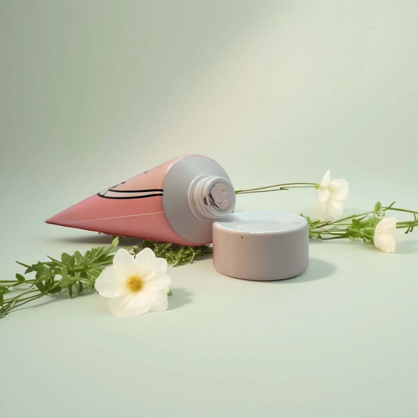 Bonnyhill Strawberry Milk Cream tube with cap, floral backdrop.