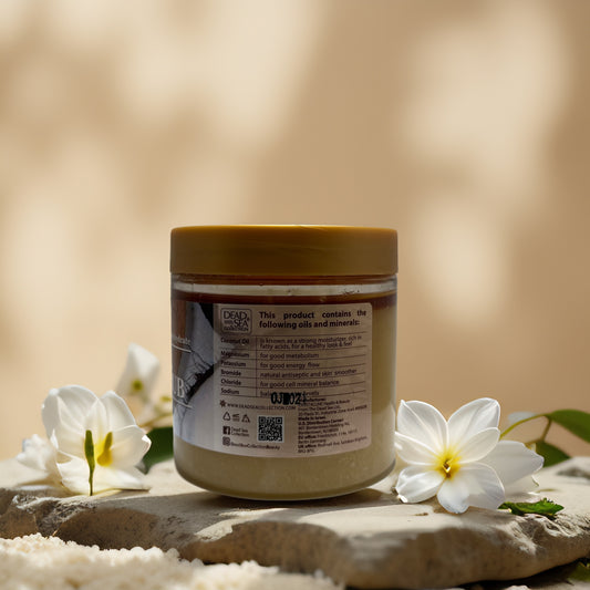 Hydrating exfoliation coconut mineral salt scrub from Dead Sea collection, with floral arrangement, features oils and minerals.
