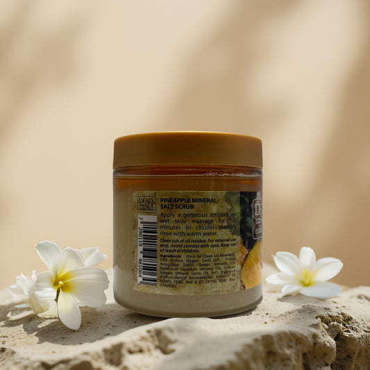 Pineapple Mineral Salt Scrub from Dead Sea Collection in jar with floral accents, perfect for brightening exfoliation.