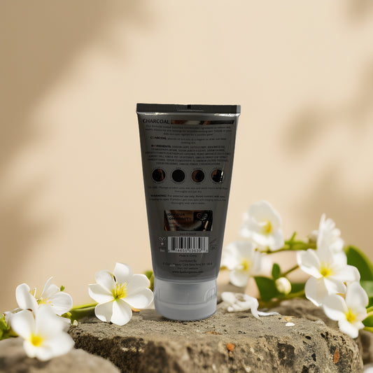 Back view of SpaScriptions Charcoal Exfoliating Facial Scrub tube with floral accents.