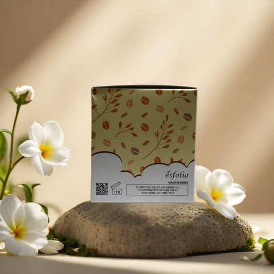 Esfolio Rice Cleansing Pad packaging on a stone with flowers, highlighting gentle exfoliation and brightening benefits.