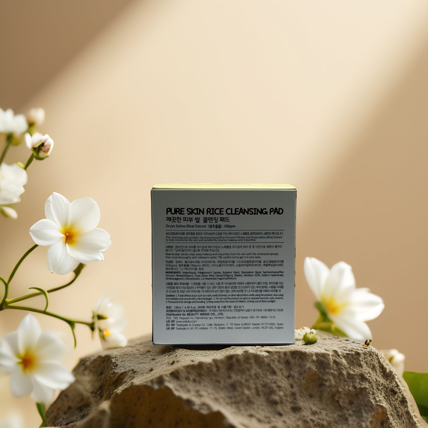 Esfolio Rice Cleansing Pad packaging on a stone, features gentle exfoliation and brightening for fresh skin.