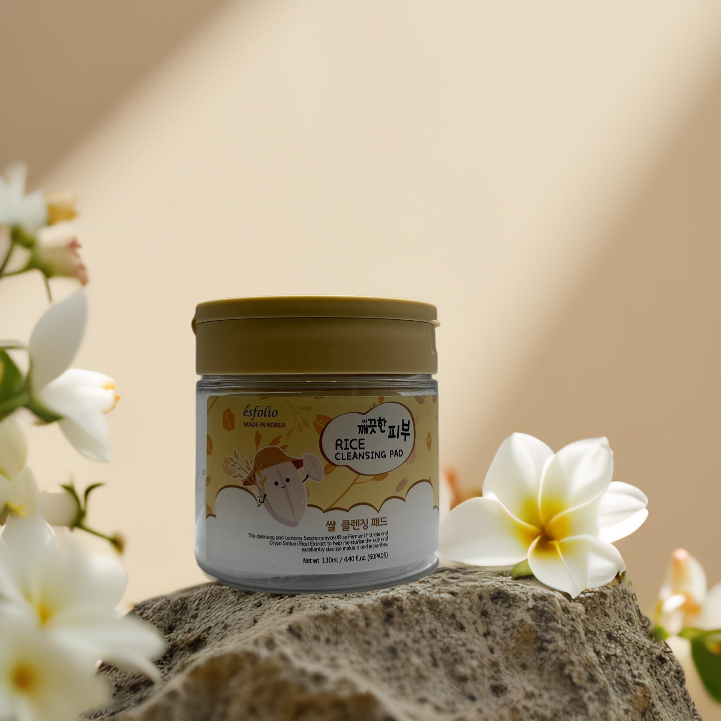Esfolio Rice Cleansing Pad jar on stone with flowers, designed for gentle exfoliation and brightening of the skin.