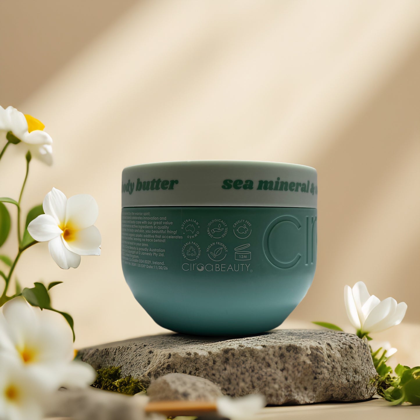 Circa Beauty Sea Mineral Body Butter jar on a stone, surrounded by flowers, showcasing eco-friendly packaging.