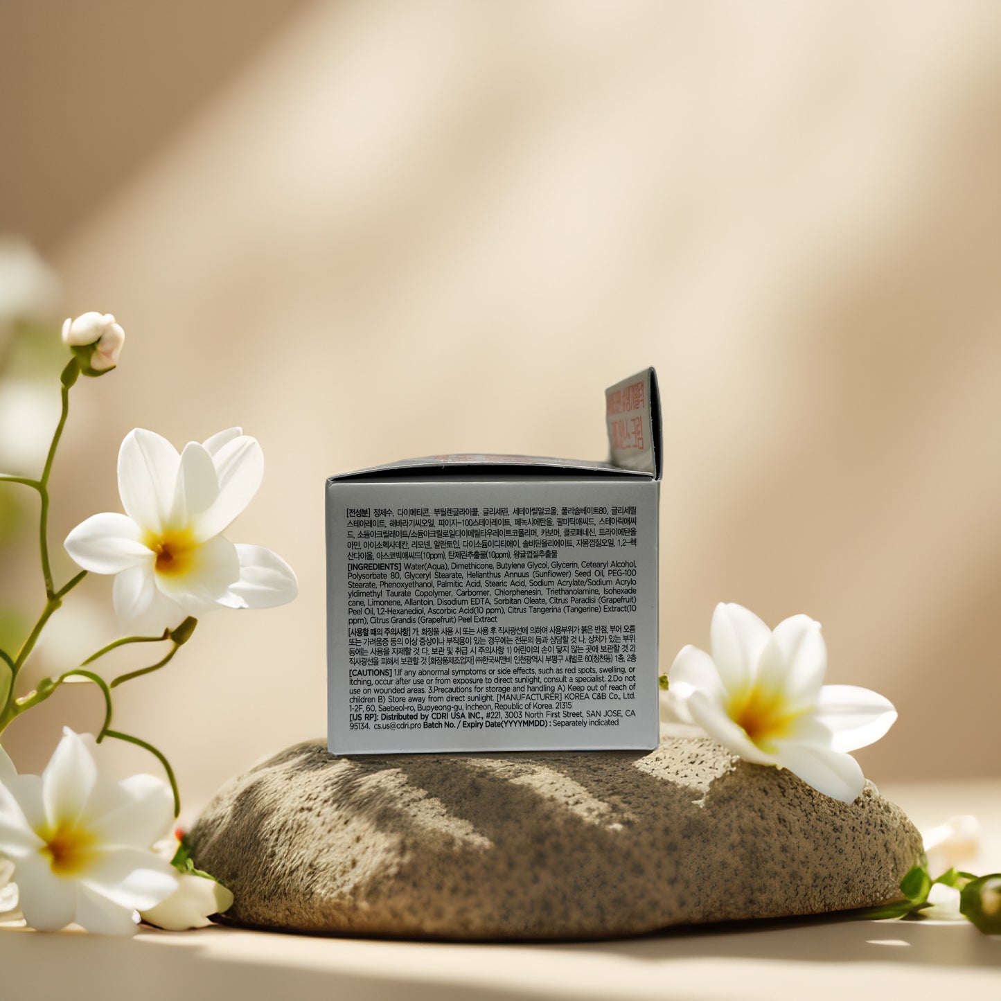 Vitamin C Radiance Cream by Tenzero on a stone with flowers, showcasing product ingredients and packaging.