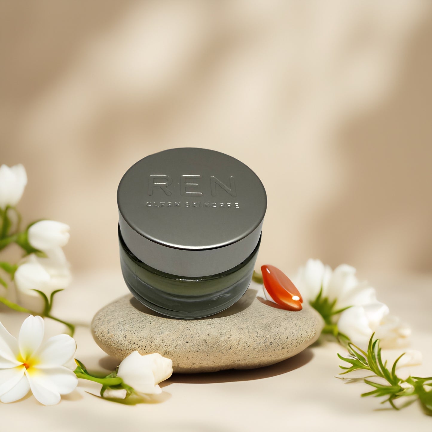 REN Clean Skincare Evercalm Rescue Mask on stone with flowers, hydrating cream for sensitive skin.