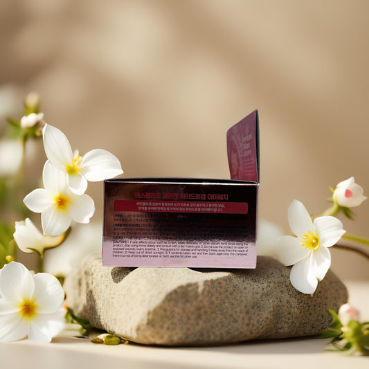 Collagen hydrogel eye patch box by Esfolio, surrounded by white flowers on a stone background.