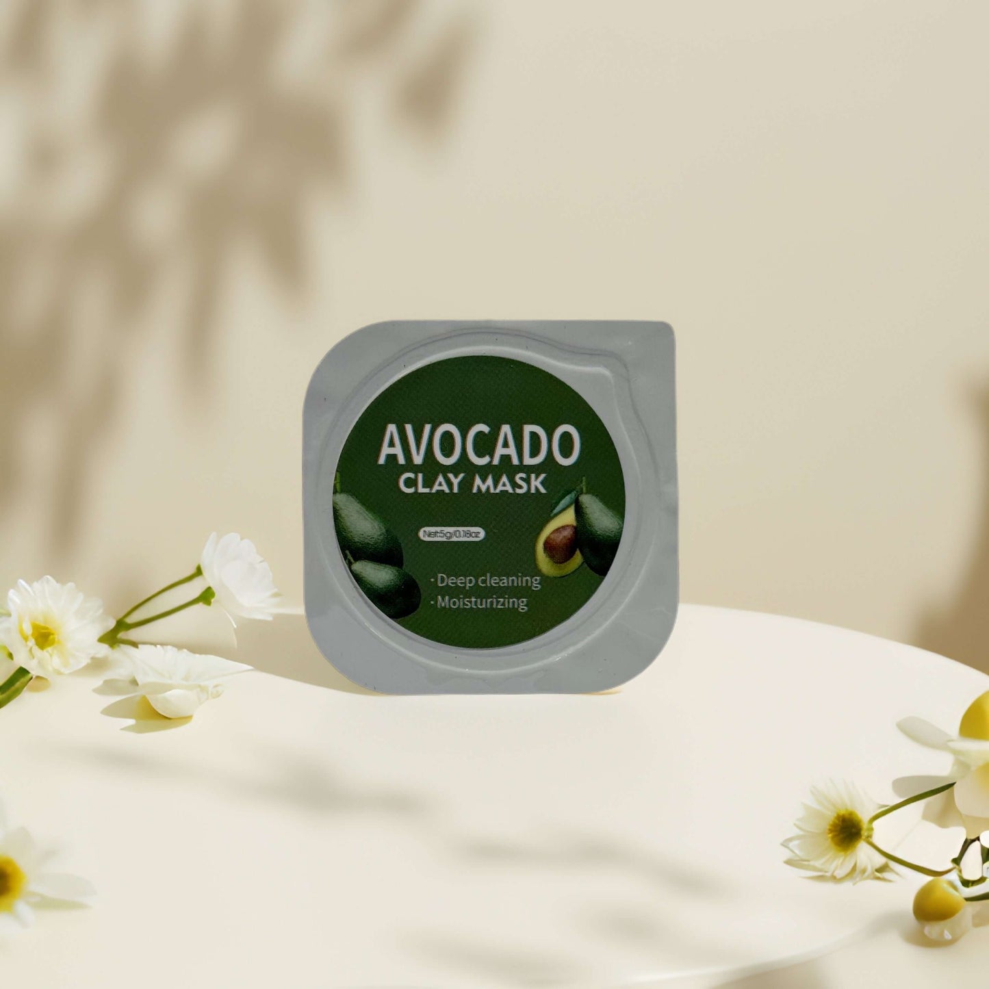 Avocado clay mask pod for deep cleaning and moisturizing skin, placed on a minimalist table with flowers.