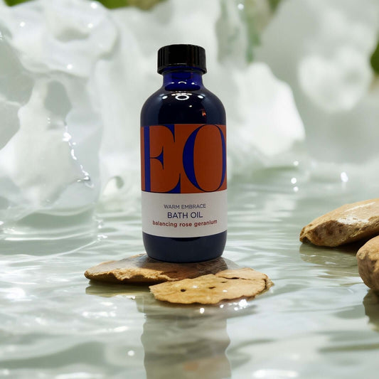 EO Body Boost Bath Oil with rose geranium in a serene setting.