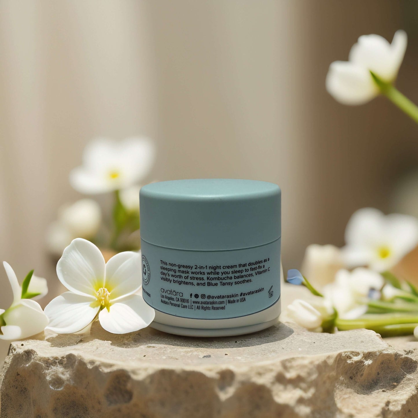 KOM-BU-CHA Sleep Mask by Avatara on a stone surface with flowers, promoting calm and bright skin overnight.