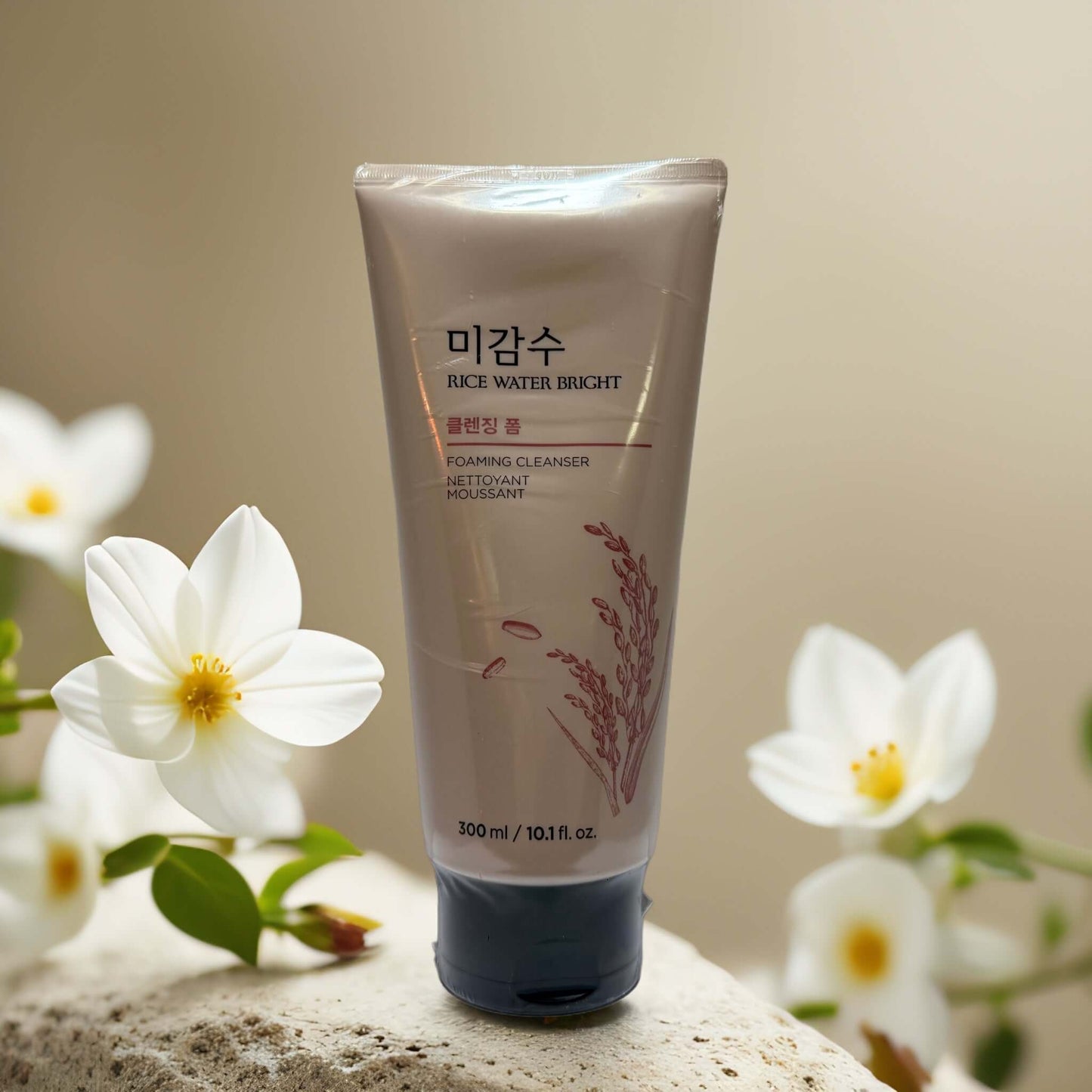 The Face Shop Rice Water Bright Foaming Cleanser tube surrounded by white flowers, 10.1 fl oz, brightening skincare.
