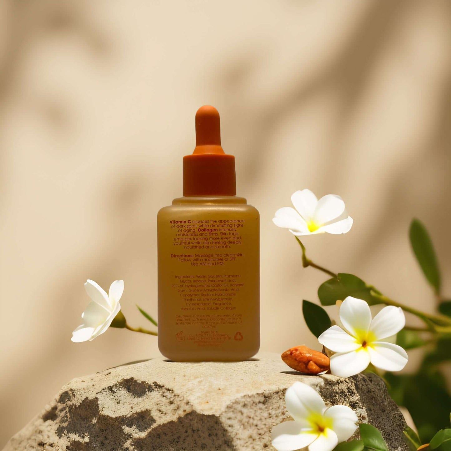 Vitamin C face serum from Glow Elixir on stone with white flowers, ideal for brightening and firming skin.