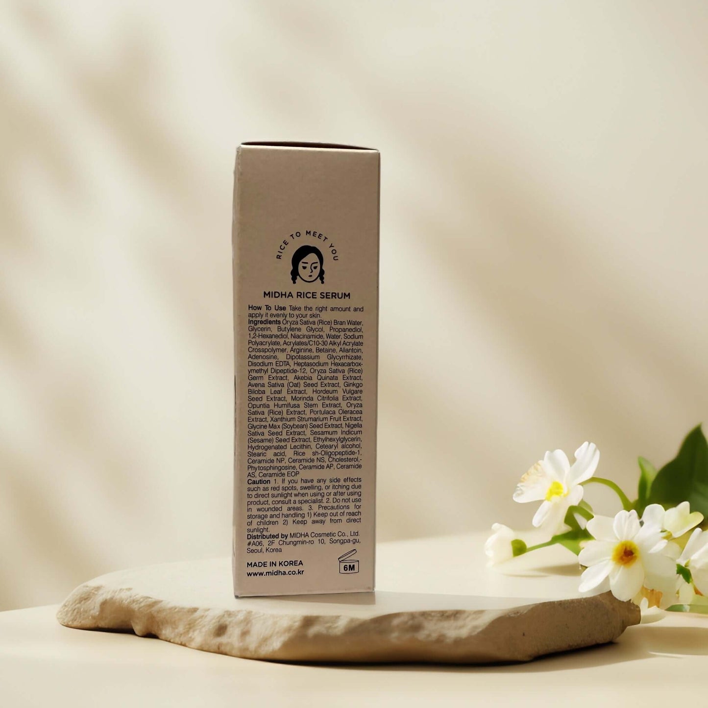 MIDHA Rice Serum packaging on a beige surface with flowers