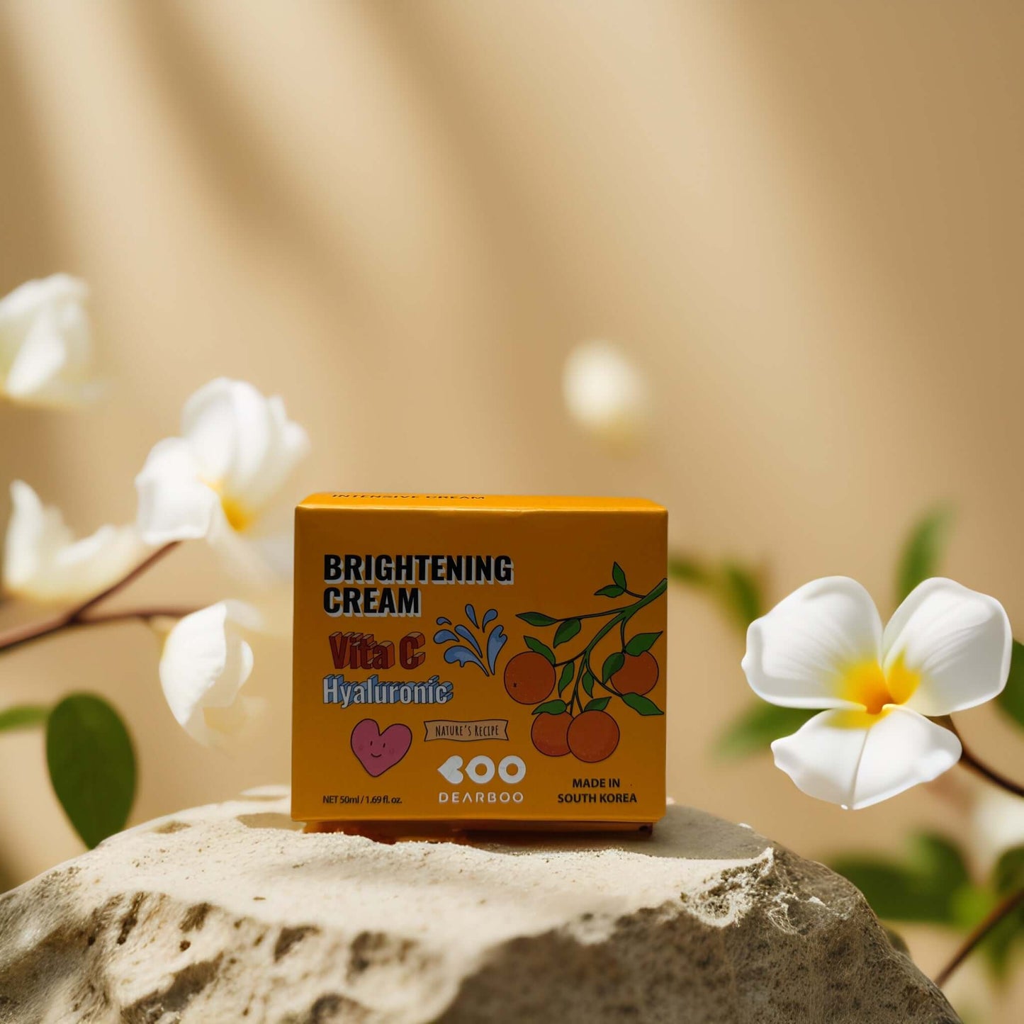 Brightening cream box featuring Vitamin C and Hyaluronic Acid by Dearboo, surrounded by flowers on a stone.