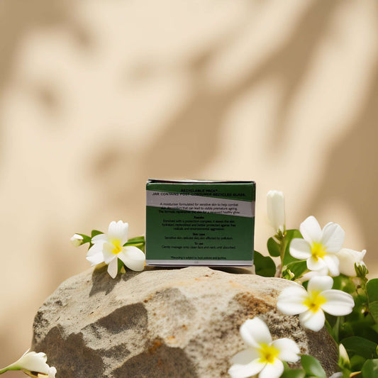 REN Global Protection Day Cream on a rock surrounded by flowers, ideal for soothing sensitive skin.