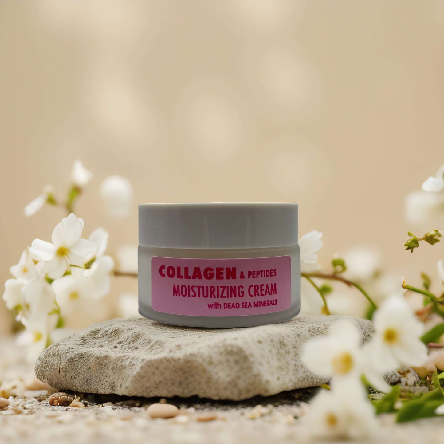 Collagen and peptides moisturizing cream with Dead Sea minerals, displayed on a stone surrounded by flowers.