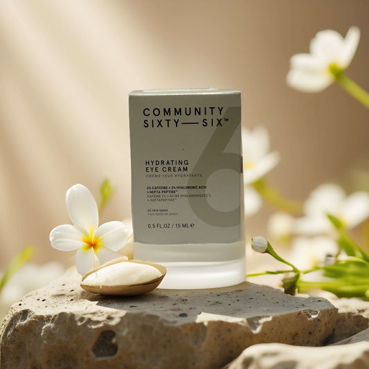 Bright-Eyed Boost Hydrating Eye Cream by Community Sixty-Six, with caffeine and hyaluronic acid, on a natural stone backdrop.