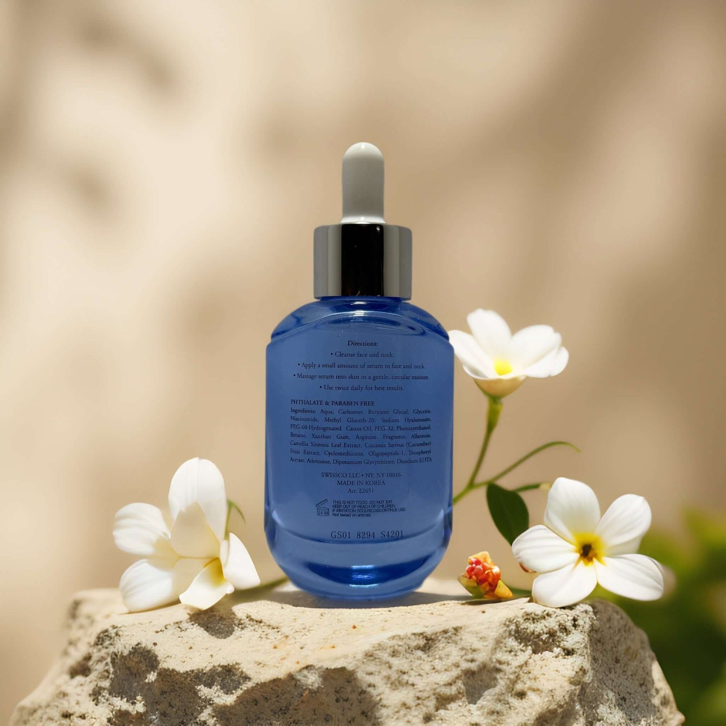 Cool & Calm Hyaluronic Acid Serum on a stone with flowers, showcasing hydration and refreshing skincare.