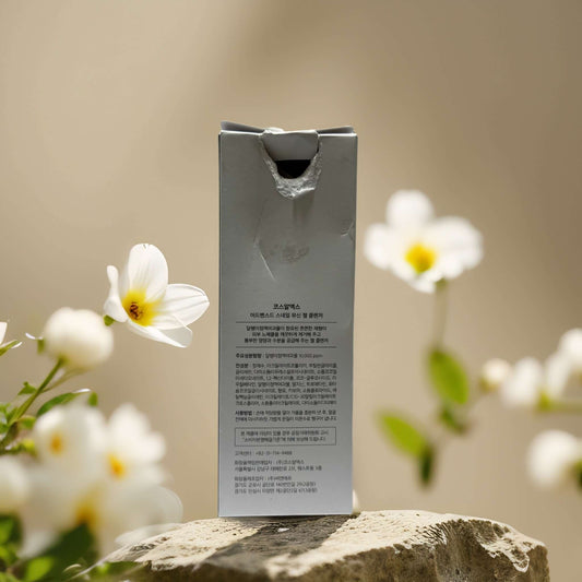 Back of COSRX Snail Mucin Gel Cleanser packaging surrounded by flowers, showcasing product details.