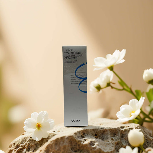 COSRX Triple Hyaluronic Cleanser packaging surrounded by flowers, 5.1 fl oz, ultra-moisturizing facial cleanser.