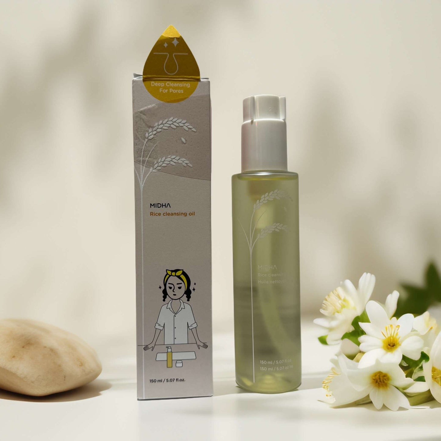 MIDHA Rice Cleansing Oil with packaging and white flowers.