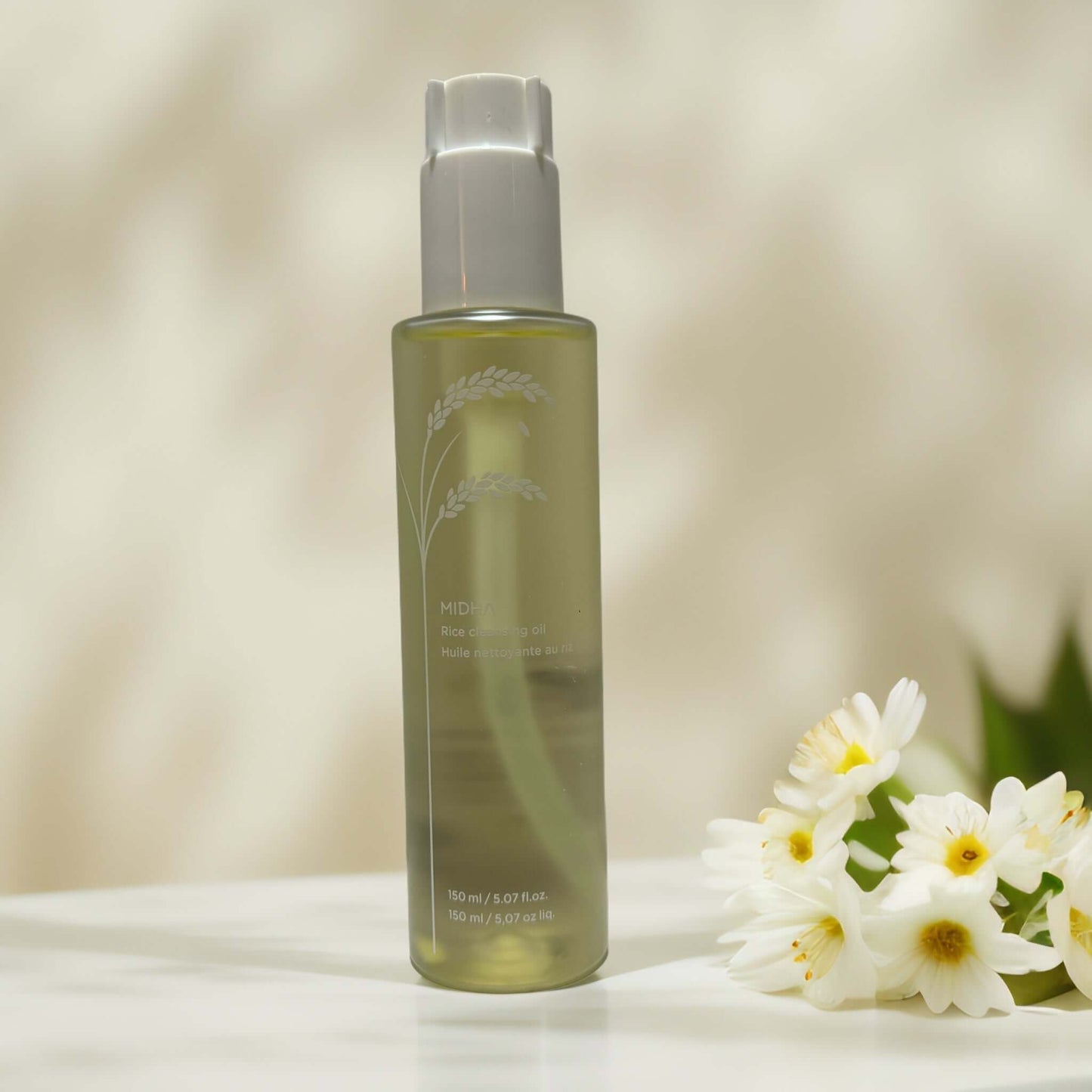 MIDHA Rice Cleansing Oil bottle with white flowers nearby.