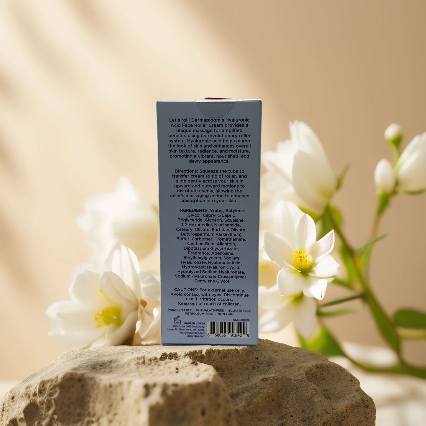 Back view of Dermabloom Firming Hydration Face Roller Cream showing ingredients and instructions on a stone background.
