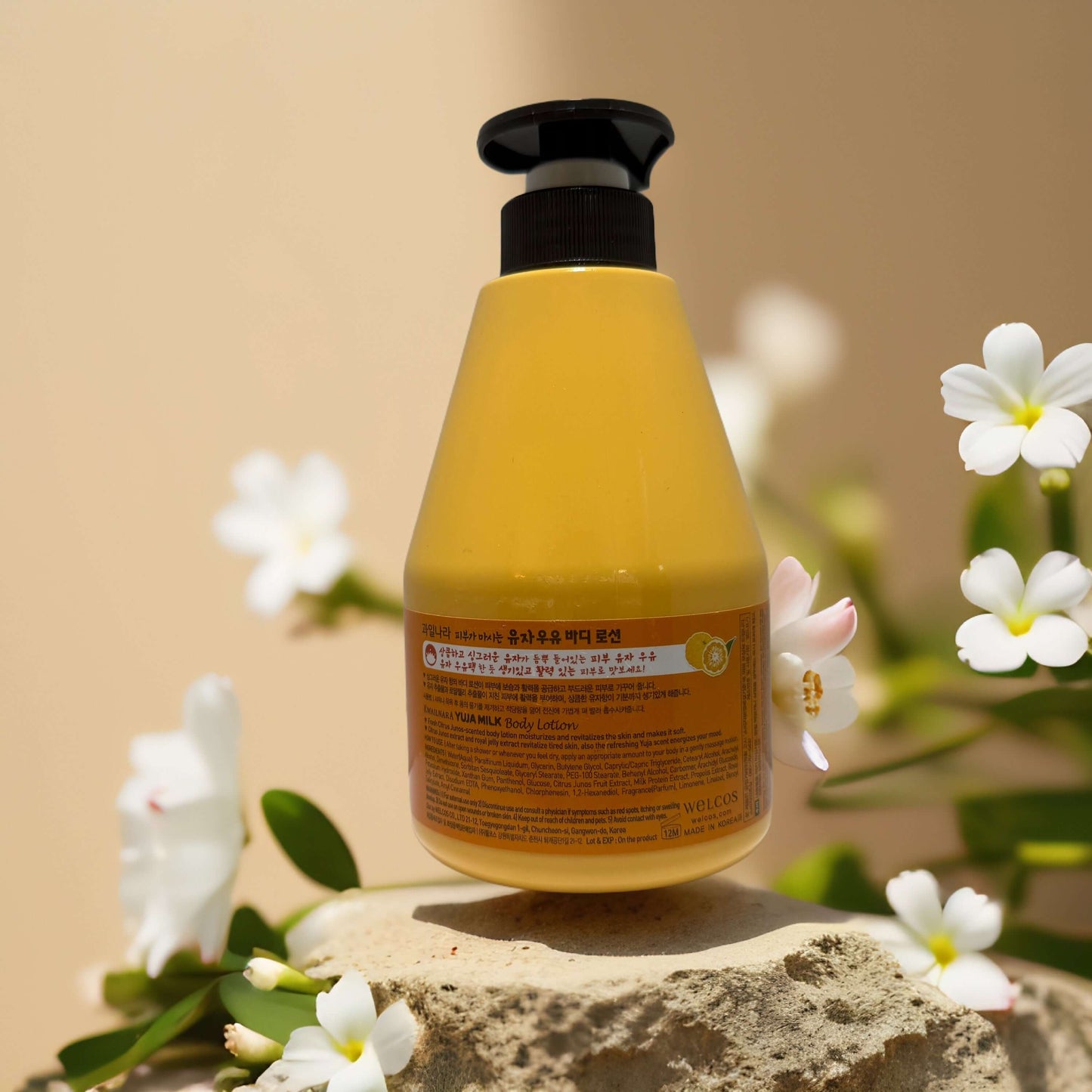 Kwailnara Yuja Milk Body Lotion bottle on a rock, showcasing its citrus scent and moisturizing benefits.