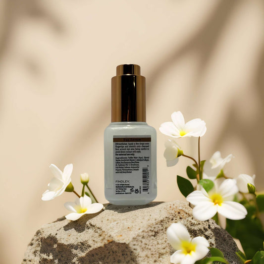 Eye serum with collagen and caffeine by Findley, designed to firm and brighten under-eye skin, surrounded by flowers.