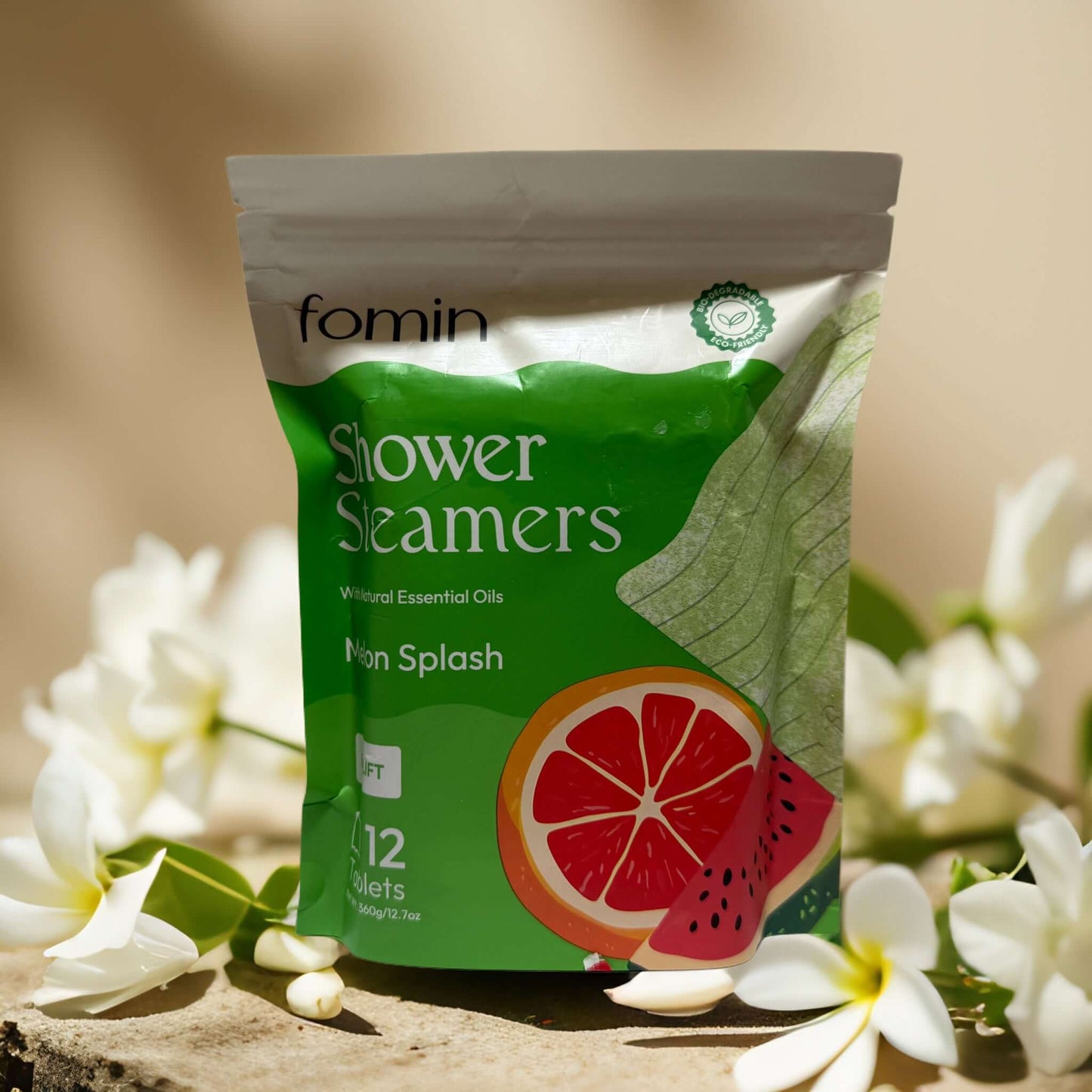 Fomin Shower Steamers packaging featuring grapefruit and watermelon, infused with essential oils, set among white flowers.