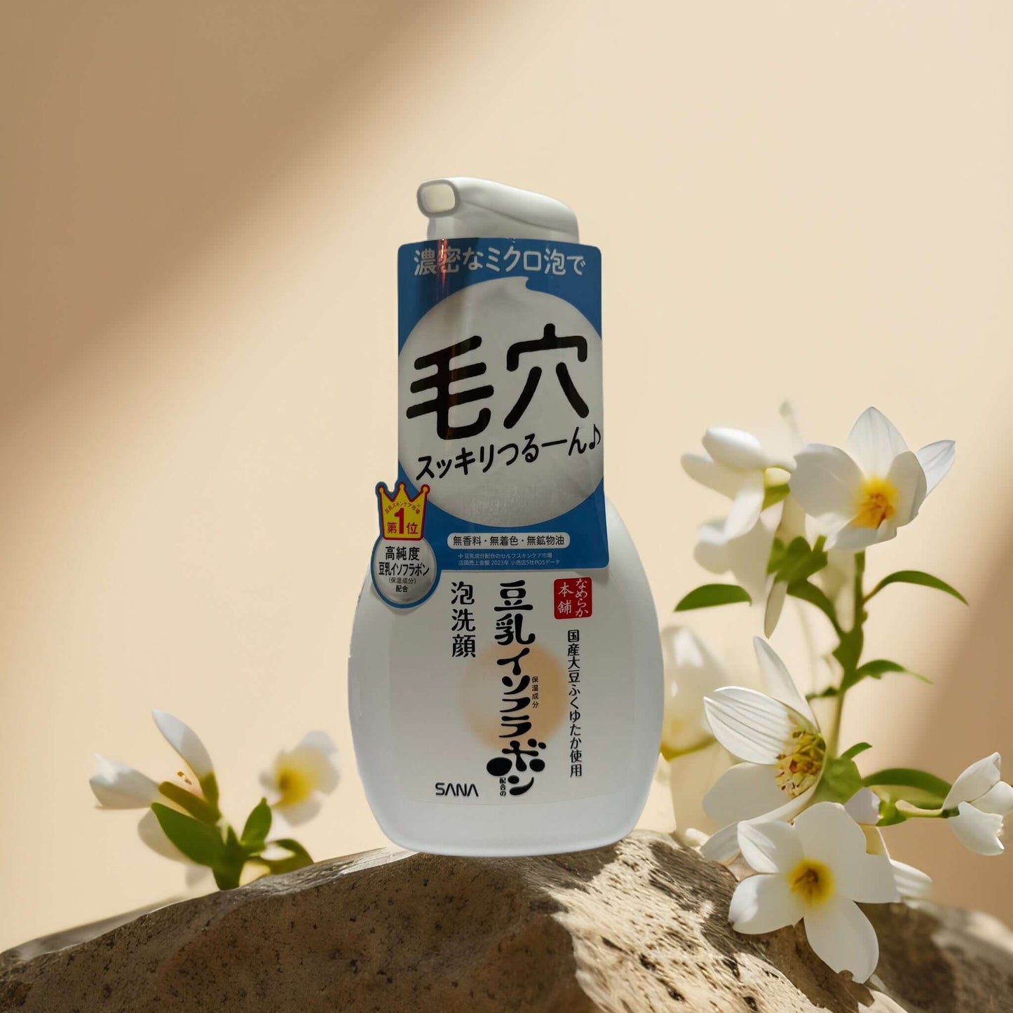 Sana Gentle Pore Cleanse Soy Milk Foaming Face Wash bottle surrounded by flowers on a stone surface.