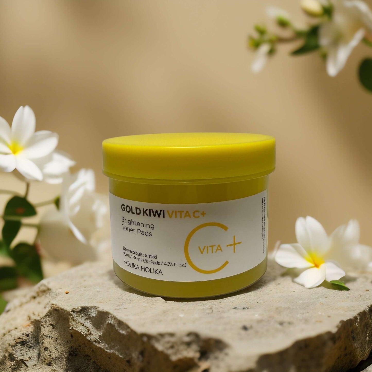 Gold Kiwi Brightening Toner Pads by Holika Holika in a vibrant yellow jar on a natural backdrop.