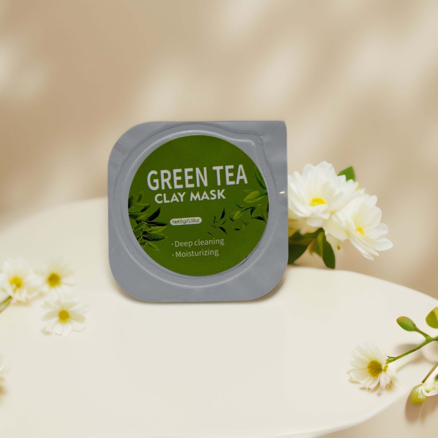 Green Tea Clay Mask pod on white surface with flowers, promoting deep cleansing and moisturizing benefits.
