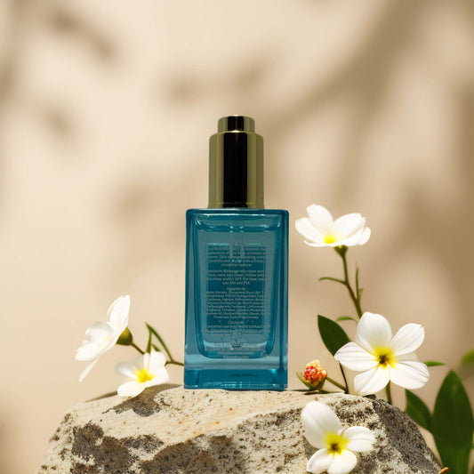 Hydration + Clarity Boost Hyaluronic Face Serum from The Beauty Nectar, 2.1 fl oz, on a stone surrounded by flowers.