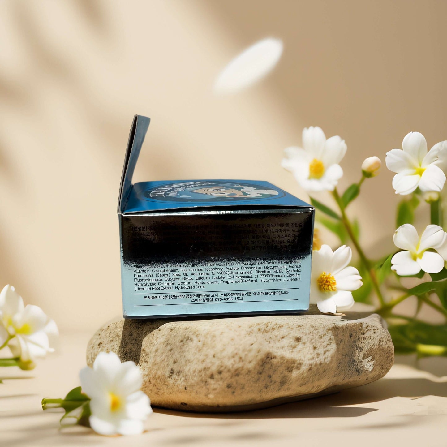 Hyaluronic Hydrogel Eye Patch packaging on a stone with flowers in the background, showcasing product details.