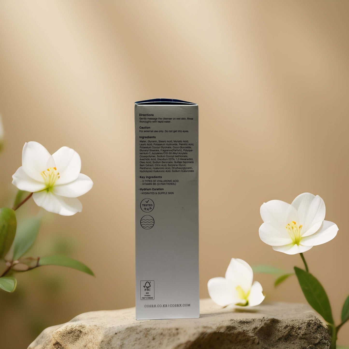 Back of COSRX Triple Hyaluronic Cleanser box with ingredients and instructions, surrounded by white flowers.
