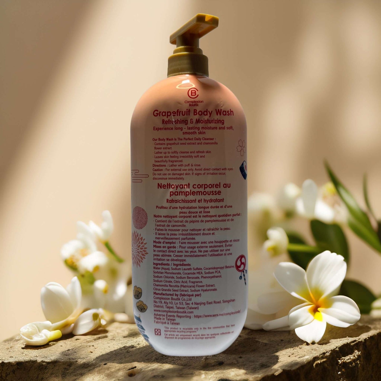 Grapefruit body wash from Complexion Boutik, hydrating cleanser with chamomile and hyaluronic acid, surrounded by flowers.