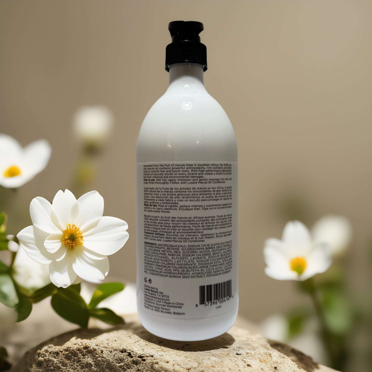 Back view of Luseta Hydrating Volume Boost Marula Oil Shampoo bottle with floral background.