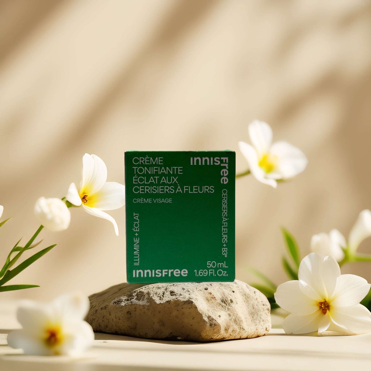 Innisfree Cherry Blossom Tone-Up Cream on a stone with flowers, highlighting radiant skin benefits.