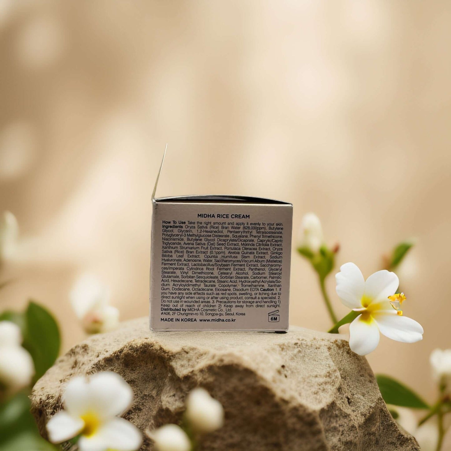 MIDHA Rice Facial Cream jar with ingredient list, surrounded by flowers, highlighting natural skincare.