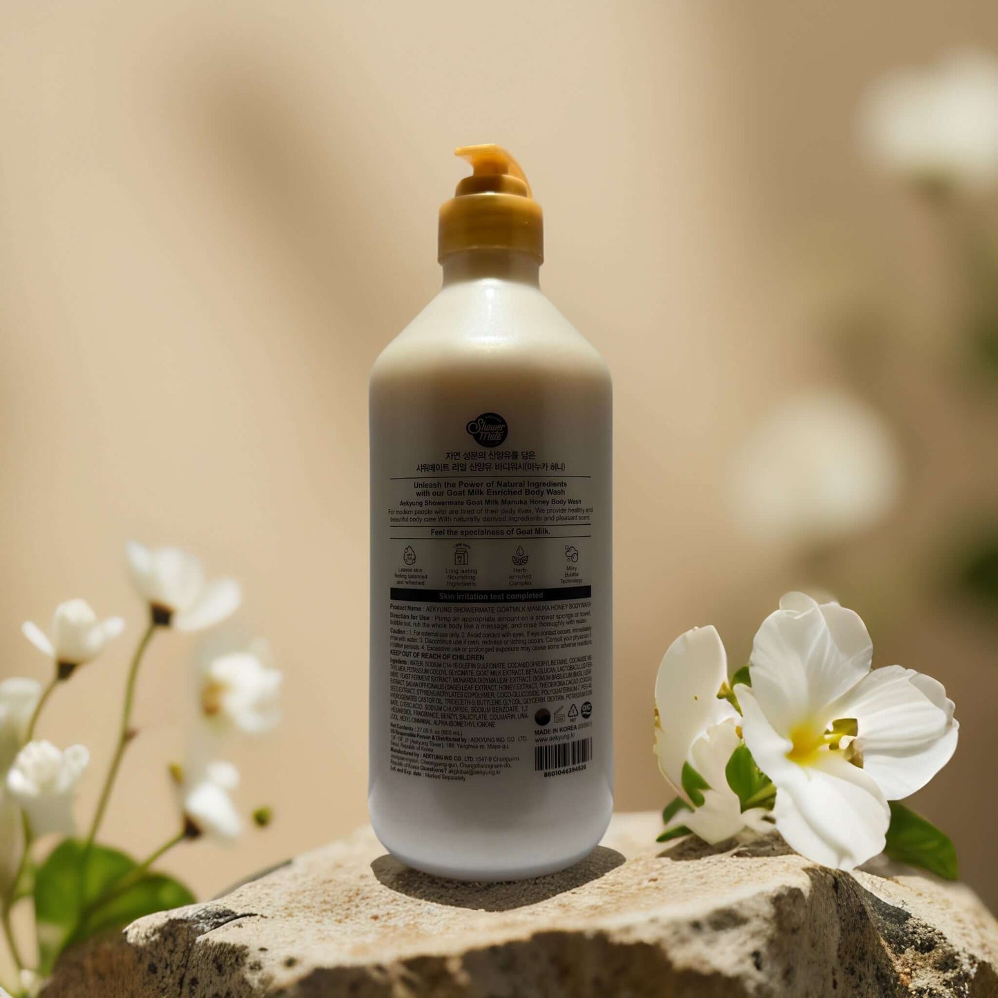 Nourish & Soothe Goat Milk Honey Body Wash bottle surrounded by flowers, 27.1 oz for hydrated, smooth skin.