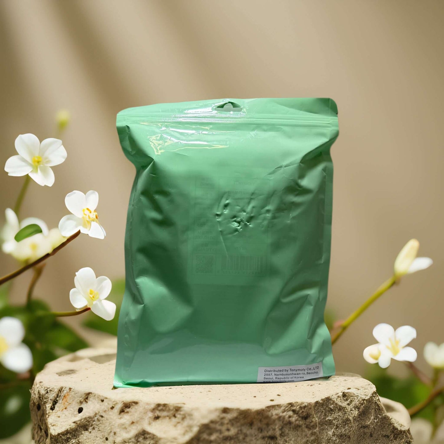 Nourishing sheet mask set packaging by TonyMoly on a stone surface with white flowers in the background.