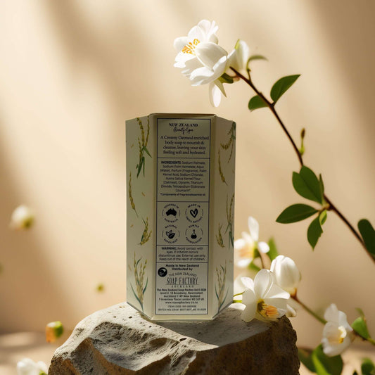 Back view of NZ Beauty Spa creamy oatmeal soap packaging with ingredient details on a stone surface.