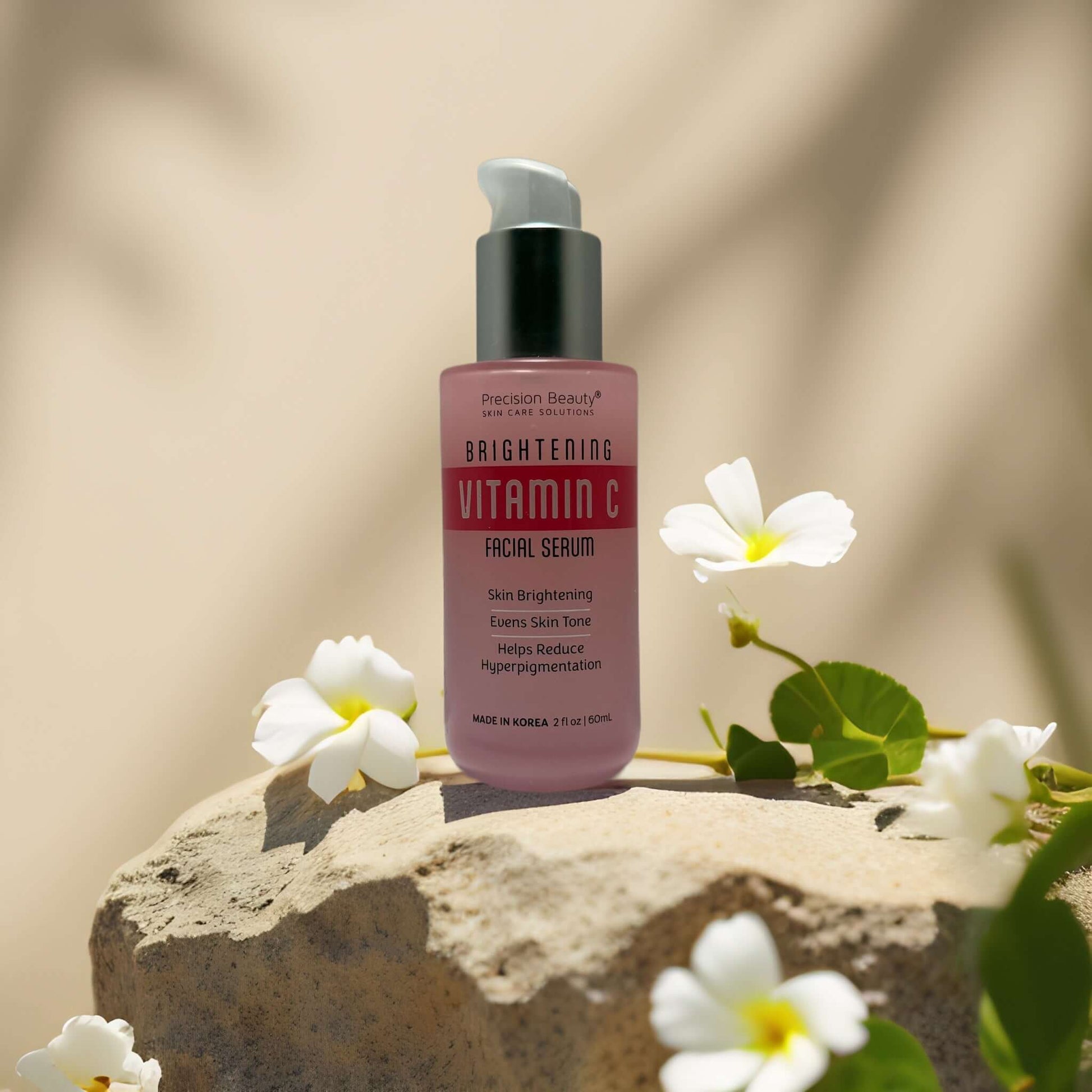 Brightening Vitamin C Face Serum by Precision Beauty on a stone surface with flowers, targeting dull skin and hyperpigmentation.