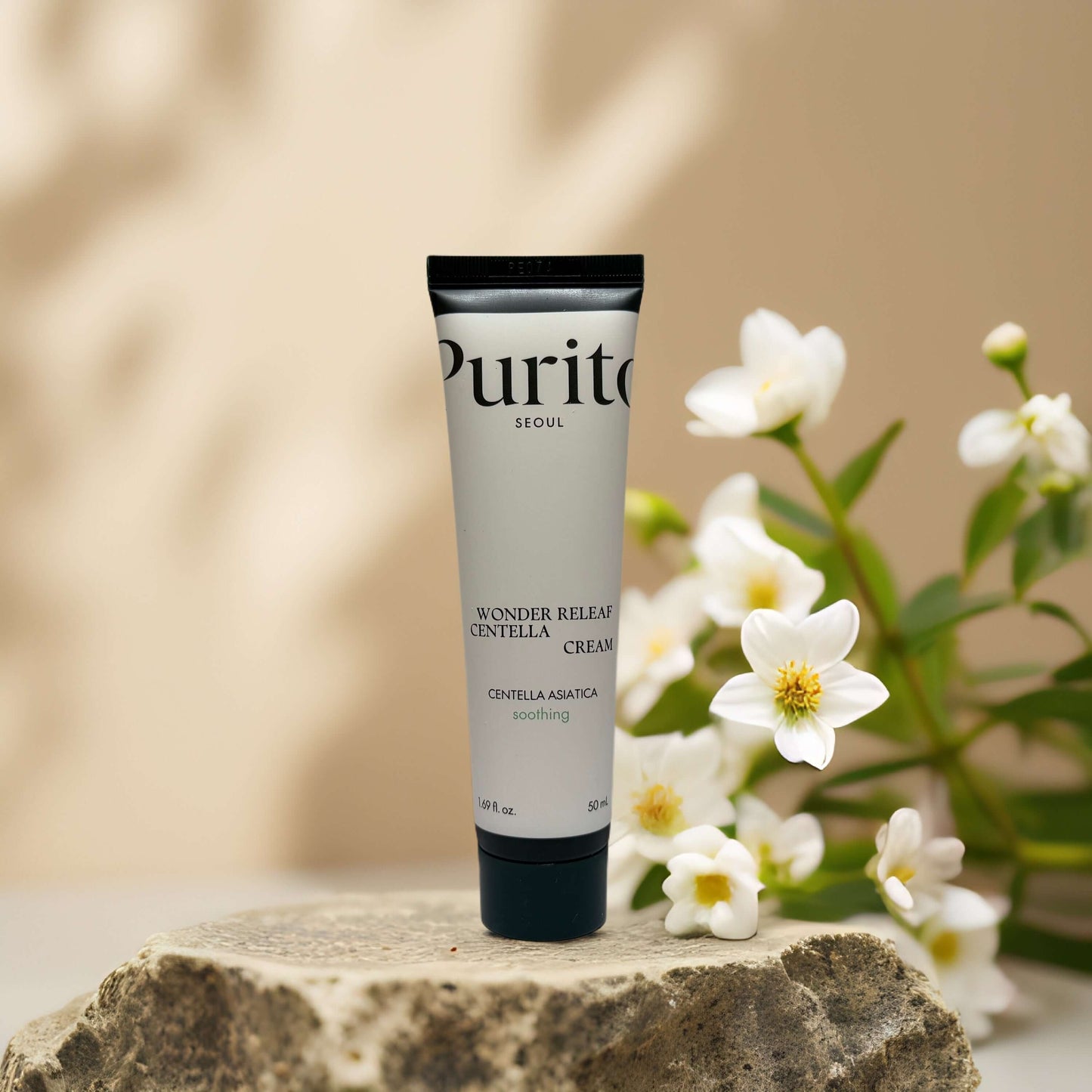 Purito Wonder Relief Centella Cream on a stone with flowers, soothing formulation for sensitive skin, 1.7 fl oz.