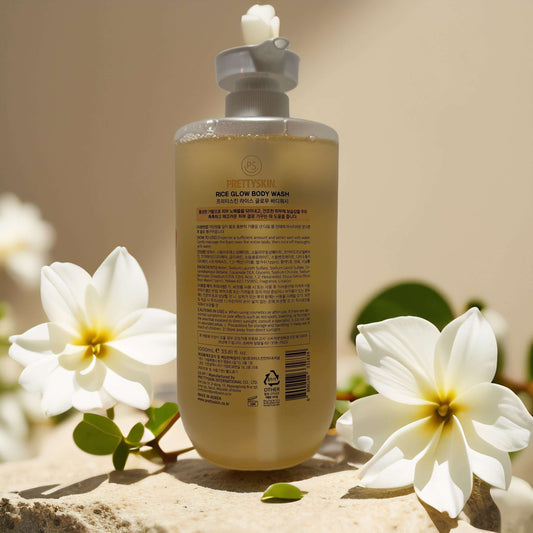 PRETTYSKIN Rice Glow Body Wash bottle surrounded by white flowers, promoting radiant skin and hydration.