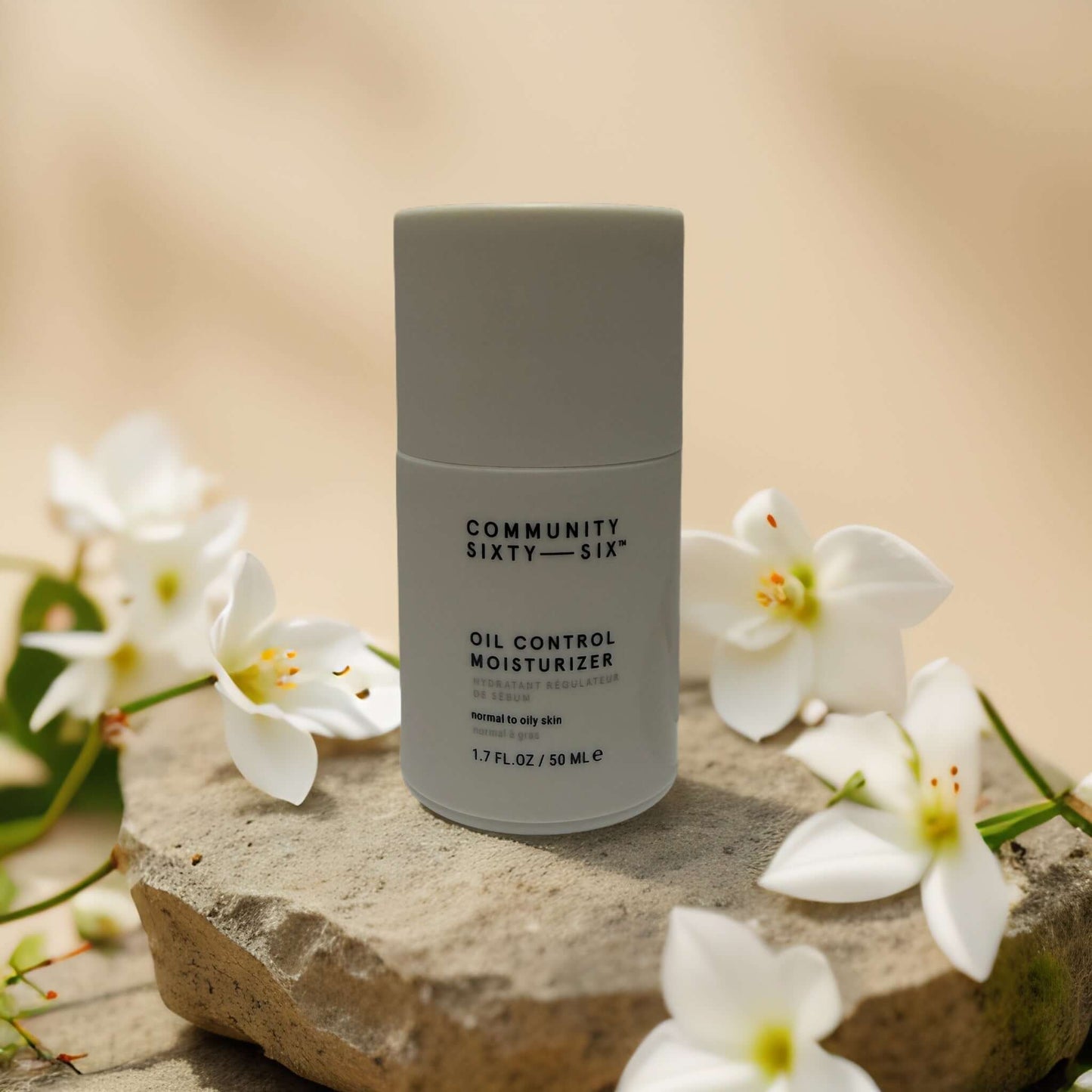 Shine-Free Balance Oil Control Moisturizer by Community Sixty-Six on stone with white flowers, 1.7 fl oz for oily skin.