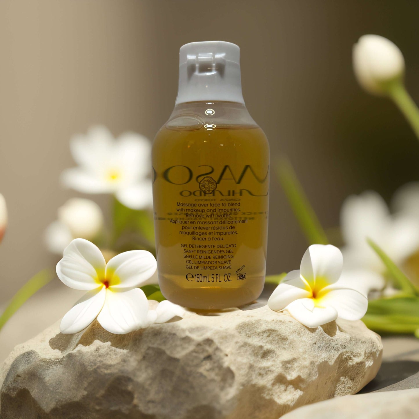 WASO Shiseido gentle daily gel cleanser bottle on stone, surrounded by white flowers, showcasing a natural skincare product.