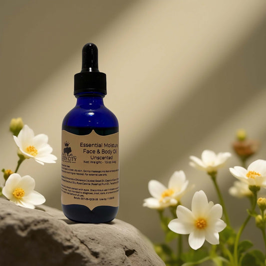 Unscented Face and Body Oil from QCS in blue bottle, surrounded by flowers on a rock, 1.7 fl oz.